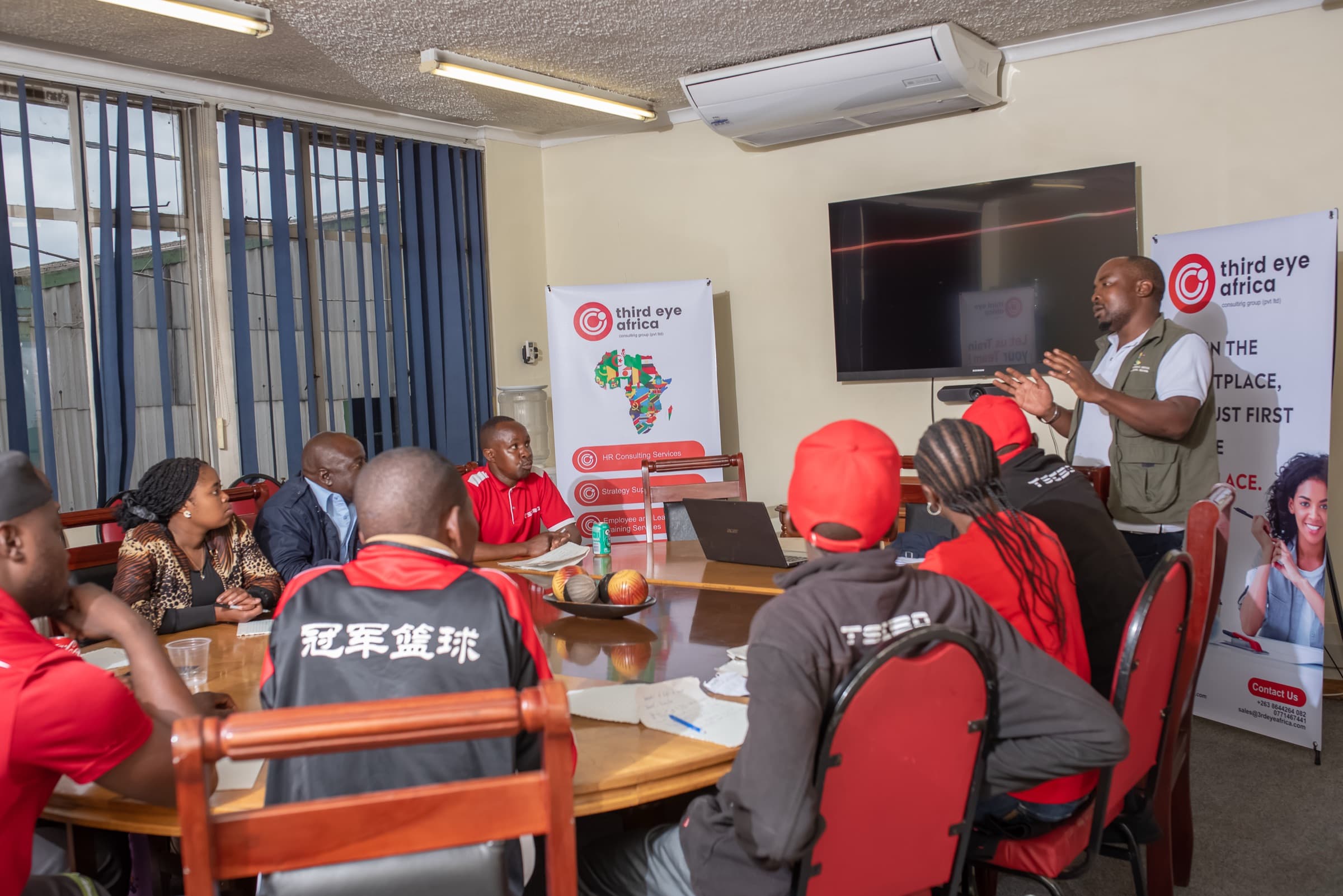 A trainer addressing a room of employees in red uniforms
